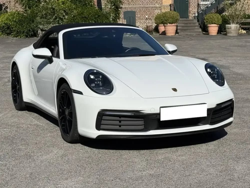 Porsche 911 992 Cabriolet bianca con la capote aperta, vista di tre quarti anteriore
